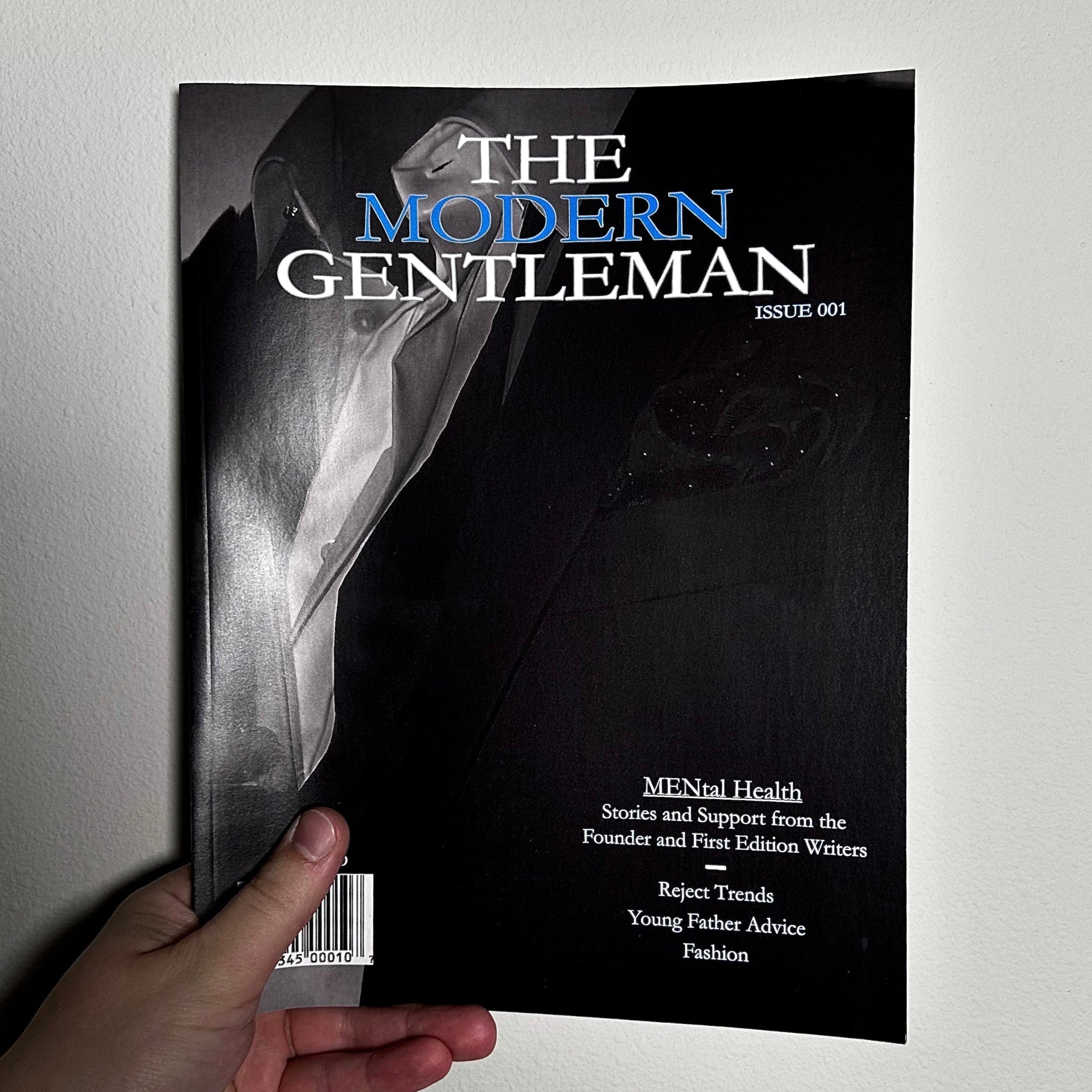 Book titled 'The Modern Gentleman' held by a hand against a light gray background